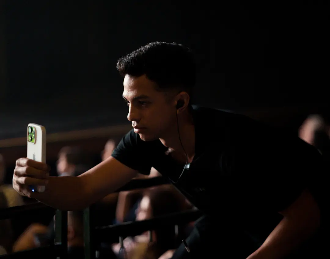 Integrante da equipe filmando com o celular entre as poltronas